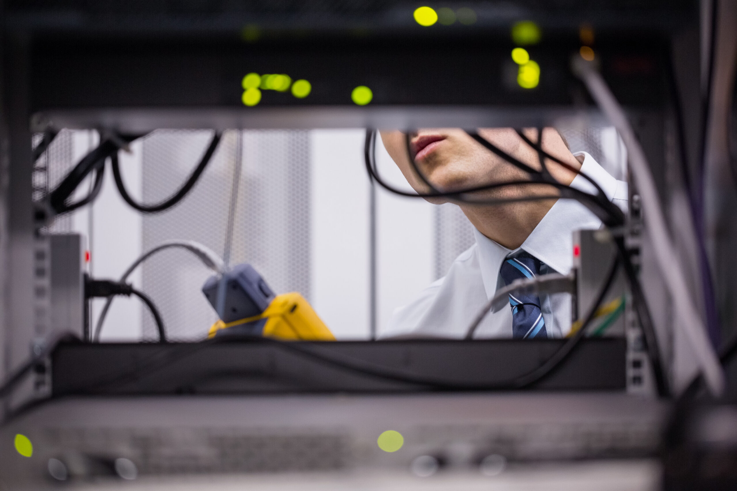 Technician using digital cable analyzer on server in large data center