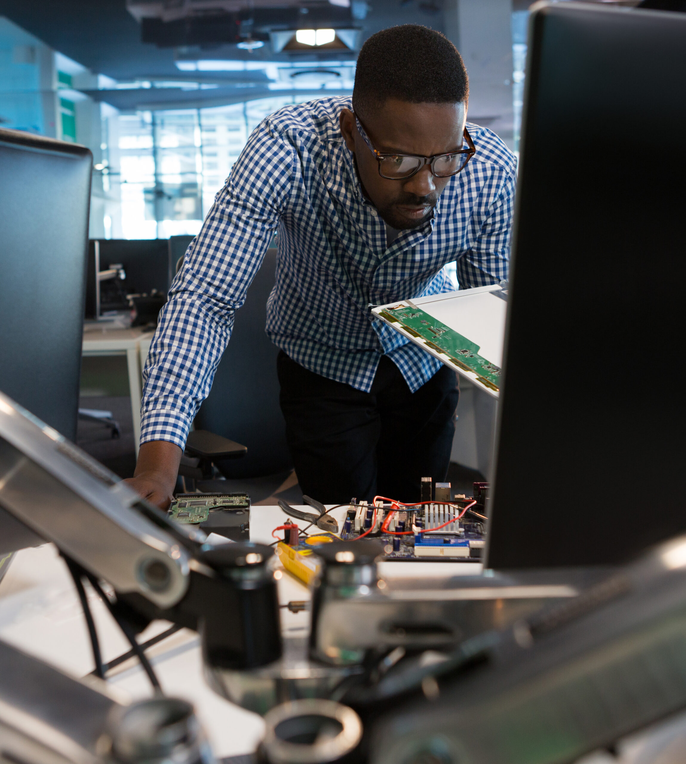 Computer engineer repairing motherboard at desk in office