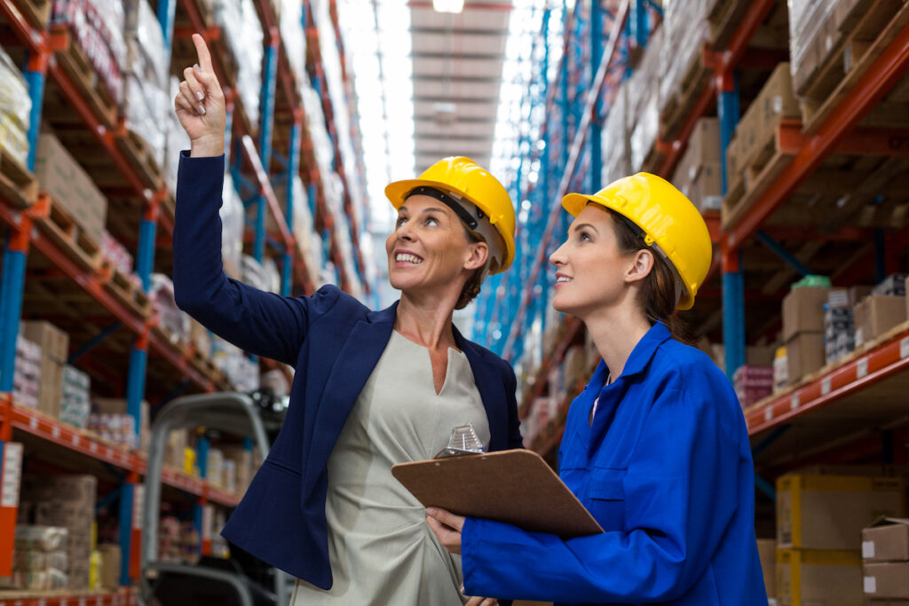 two women in yellow hard hats on warehouse floor
